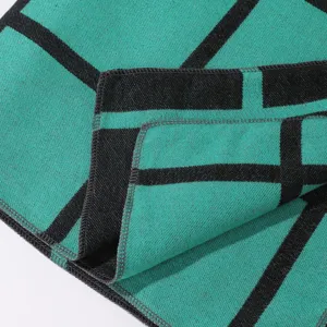 Close-up detail of the green and black geometric grid pattern and fine edges of the shawl.