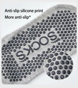 Detailed view of grey yoga socks with black non-slip grip dots on the sole for stability.