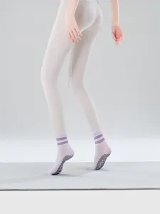 Close-up detail view of women's anti-slip yoga socks and leggings in a clean studio setting.