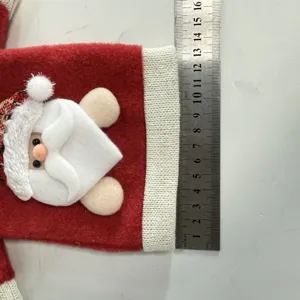 Dettaglio copri bottiglia di vino natalizio con design di Babbo Natale e polsino in maglia.