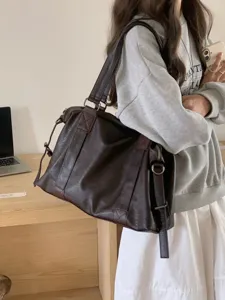 Detail shot of large capacity dark brown leather tote bag, showing premium texture and dual handles.