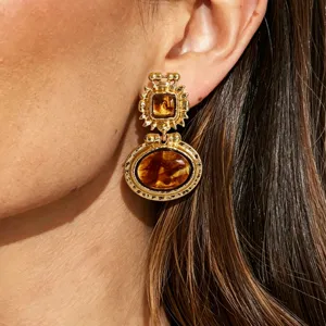 Gros plan détaillé de boucles d'oreilles pendantes rétro baroques en résine dorée.
