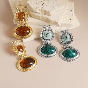 Gros plan de composants de collier pendentif en résine de style baroque vintage doré et argenté.