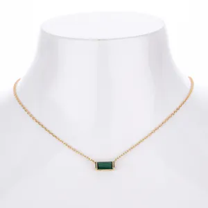 Close up of gold plated chain necklace with a rectangular green zirconia stone pendant detail.