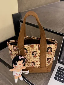 Detail view of the cute plaid canvas cosmetic bag featuring cartoon prints and doll charm.