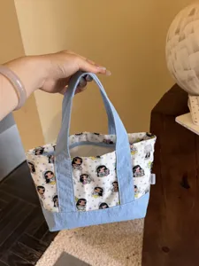 Detailed view of cute canvas tote bag with cartoon print, zipper closure and soft handle.
