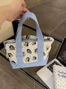 Canvas tote bag detail shot showing cute cartoon girl pattern, blue and white design, mini size.