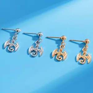 Close-up shot of miniature flying dragon stud earrings in silver and gold tone metal finishes.