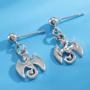 Detailed close-up of mini silver dragon earrings showing intricate wing and pendant details.