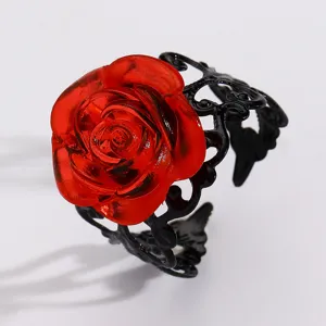 Macro detail view showing the vibrant red resin rose flower and black filigree ring band.