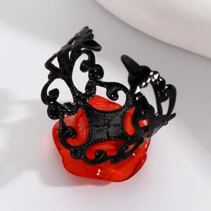 Close-up detail of the black filigree open ring on red flower display base, stylish accessory.