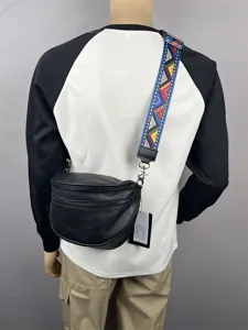 Detail view of black shoulder bag featuring colorful patterned strap and metal zippers.