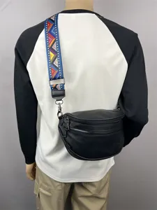 Stylish black crescent crossbody bag with colorful patterned strap, casual shoulder bag.