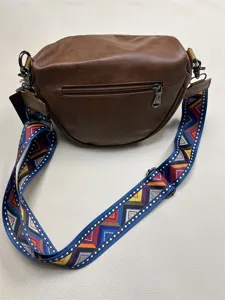 Detail view of brown PU leather crossbody bag with colorful geometric woven strap and zipper pocket