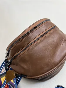 Brown leather crossbody bag with dual zippers and colorful retro shoulder strap detail shot.