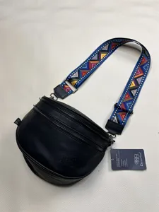 Detailed view of the stylish crossbody bag featuring colorful geometric strap and smooth zippers.