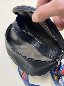 Detail view of black round crossbody bag showing multi-compartment interior and quality zippers.