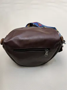 Detailed view of the dark brown leather fanny pack, featuring a back zipper and colorful strap.