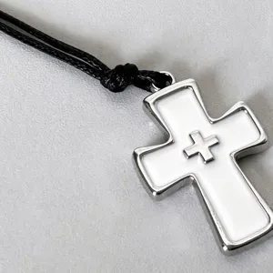 Detail shot of a vintage punk white enamel cross pendant necklace with black cord.