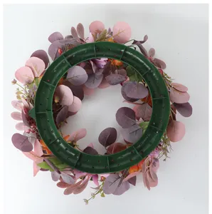 Autumn artificial flower wreath detail showing pink leaves and green ring base for home decor.
