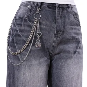 Close-up detail view of punk rock metal pants chain featuring cool skull hand pendant on jeans.