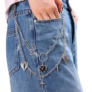 Detailed shot of multi-layer punk metal pants chain with cross and heart pendants on denim jeans.