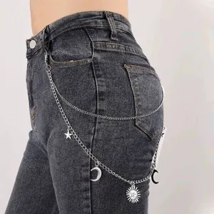 Punk style metal pants chain detail shot featuring star moon and sun pendants on jeans.