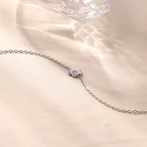 Primer plano detallado de la delicada pulsera con dije de flor y cadena de textura fina.