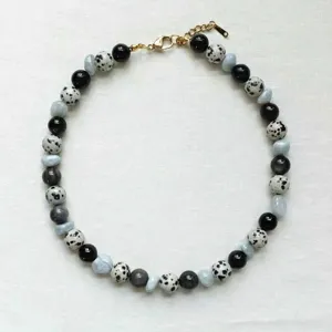 Vue détaillée d'un collier de perles tendance avec des pierres noires, mouchetées et bleues.