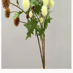 Detalle del ramo de flores artificiales con hojas verdes y tallos de frutos esféricos.