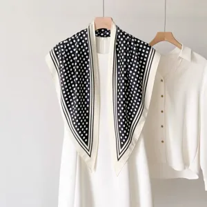 Vue détaillée d'écharpe élégante à pois noirs et blancs, châle triangulaire classique.