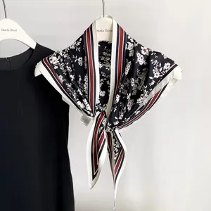 Vue détaillée d'un élégant foulard triangulaire en soie noire à motif floral et rayures.