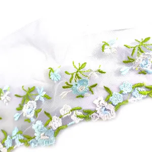 Delicate embroidered lace trim closeup showing blue and white floral mesh fabric details.