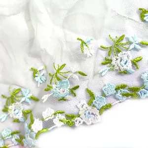 Close-up view of delicate white mesh fabric with colorful blue floral embroidery lace trim.