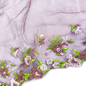 Close-up detail of purple mesh fabric with colorful floral embroidery trim for DIY sewing.