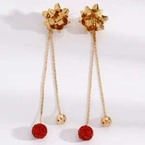 Detailed shot of Christmas style long gold earrings with bow top, red crystal ball and beads.