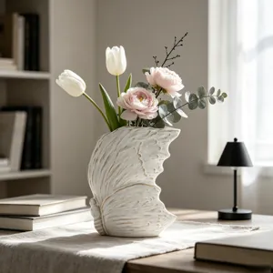 Dettaglio di vaso in ceramica con texture ala di farfalla e composizione floreale sul tavolo.