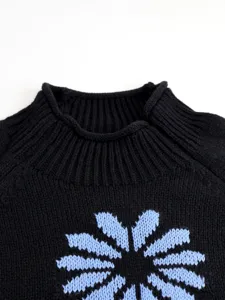Black knit pullover sweater featuring a blue floral pattern and ribbed mock neckline.