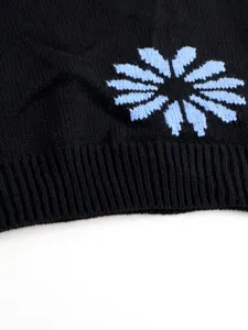Close-up detail of women's black knit sweater featuring light blue floral knit pattern.