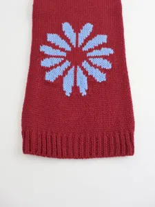 Knit sweater detail featuring a cozy red fabric with a blue floral pattern and ribbed hem.