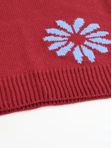 Close-up knit sweater detail featuring blue floral pattern and ribbed hem texture.