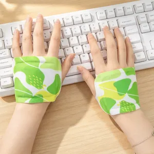 Green leaf-patterned fabric wrist supports worn while typing at a white keyboard on a wooden desk