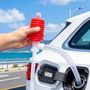 Close-up of a red hand pump and clear hose beside an open car fuel filler on a coastal road