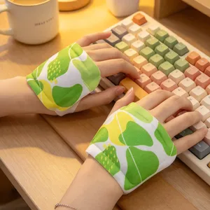 Close-up of hands wearing green leaf-print wrist warmers while typing on a colorful keyboard