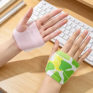 Hands wear plain pink and green leaf-patterned patches above a wooden desk and white keyboard