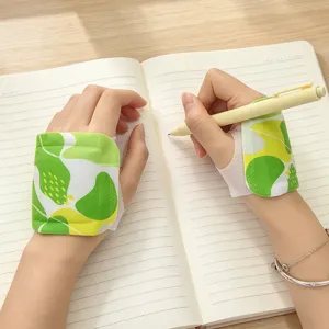 Close-up of green patterned fabric wrist supports worn while writing in an open lined notebook
