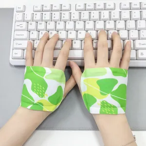 Close-up of hands using green leaf-print wrist pads at a white keyboard on a gray desk mat