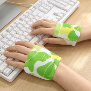 Close-up of hands wearing green leaf-print wrist pads while typing on a white keyboard