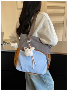 Vue de côté d’un sac porté à l’épaule, aux panneaux colorés, avec un lapin blanc en peluche