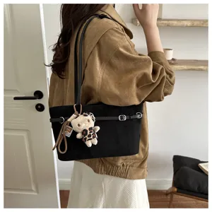 Borsa nera effetto scamosciato indossata a spalla, con fibbie metalliche e piccolo ciondolo a forma di orsetto